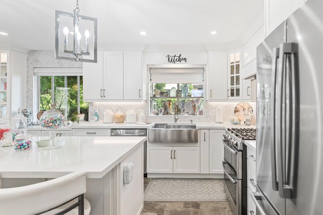 Kitchen featuring appliances with stainless steel finishes, light countertops, a sink, hanging light fixtures, and recessed lighting | Image 11