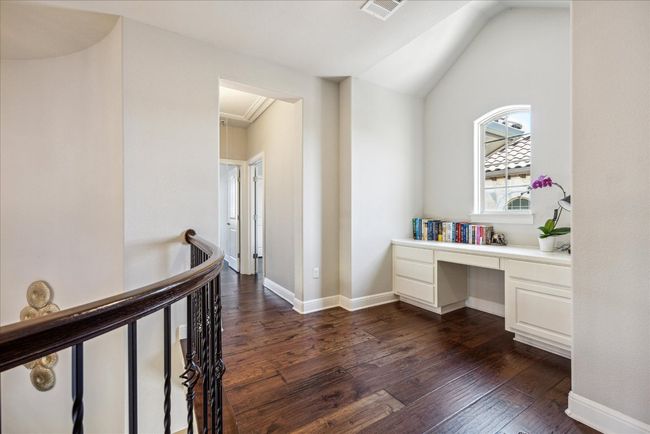 Unfurnished office with built in study area, attic access, dark wood-style floors, baseboards, and visible vents | Image 25