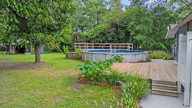 View of green lawn featuring an outdoor pool and a deck | Image 27