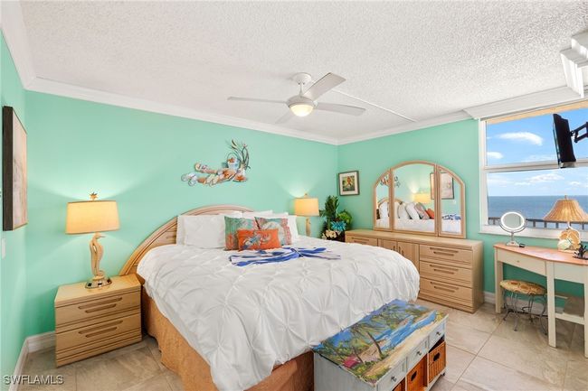Bedroom featuring crown molding, a textured ceiling, a ceiling fan, and light tile patterned floors | Image 13