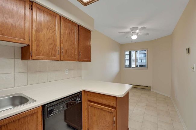 Kitchen featuring dishwasher, backsplash, a peninsula, brown cabinetry, and light countertops | Image 15