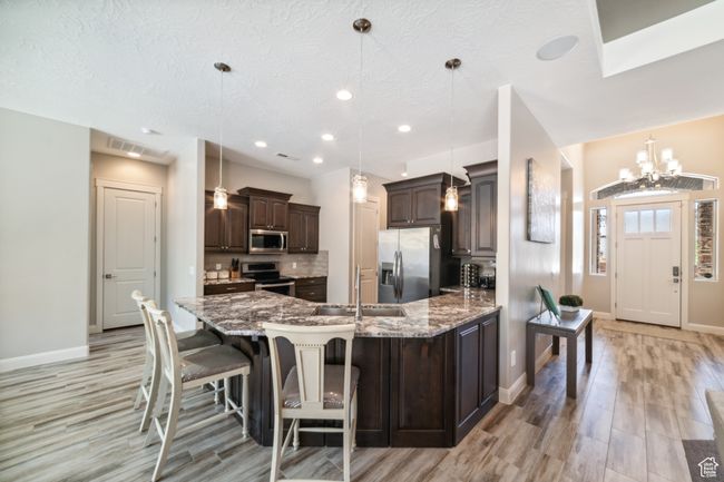 Kitchen with light wood-style flooring, a sink, baseboards, dark brown cabinetry, and appliances with stainless steel finishes | Image 10
