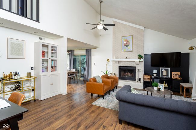 living area with wood finished floors, ceiling fan, a brick fireplace, and high vaulted ceiling | Image 6
