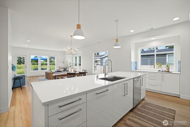 Looking across the large island with the eating bar and deep sink toward the dining area and living room. There is a lovely coffee or prep area below the window to the right of the island. | Image 11