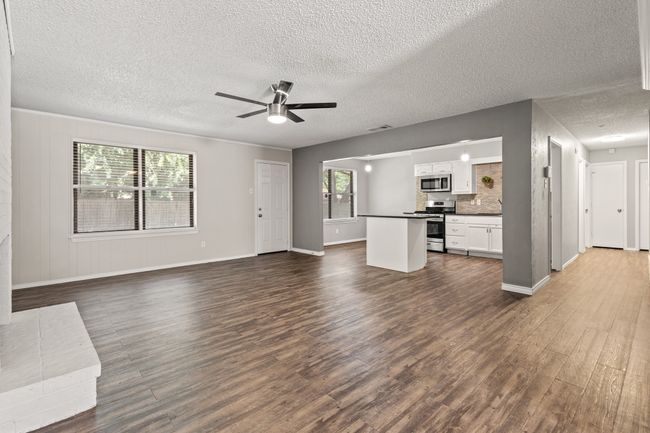 Unfurnished living room featuring dark wood-type flooring, baseboards, a textured ceiling, and a ceiling fan | Image 8