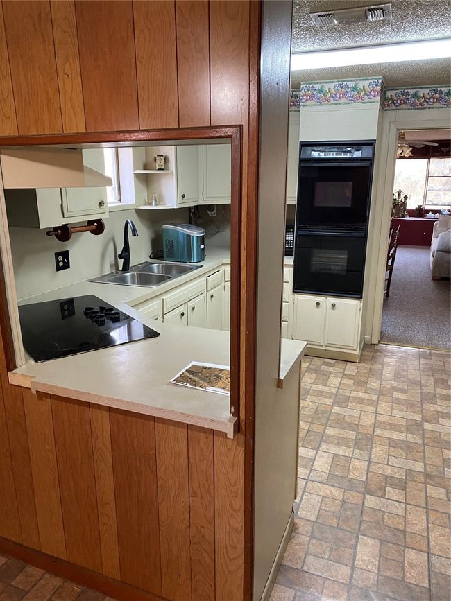 Kitchen featuring multiple ovens, stovetop, sink, and exhaust hood | Image 14
