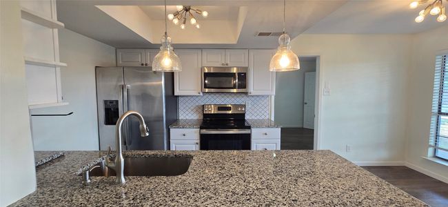 Kitchen featuring stainless steel appliances, a chandelier, white cabinets, and dark wood-style flooring | Image 11