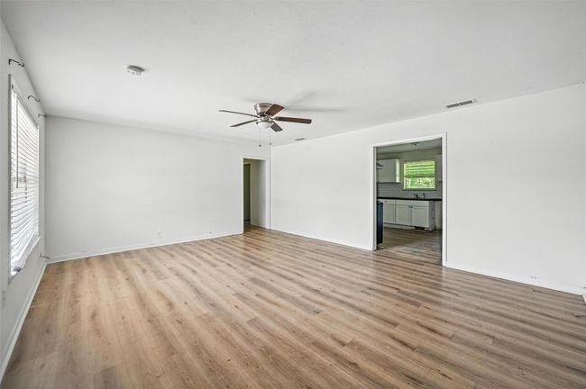 Empty room with a ceiling fan, light wood-style flooring, a smoke detector, and baseboards | Image 18