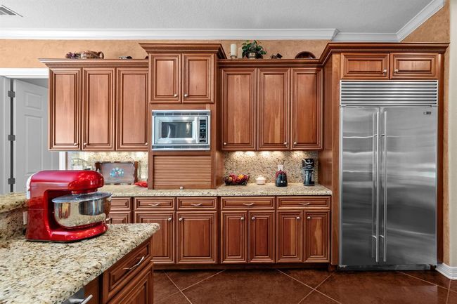 Concealed bread box/appliance garage, built-in microwave, and expansive granite counter combine style and function in one streamlined wall. | Image 18