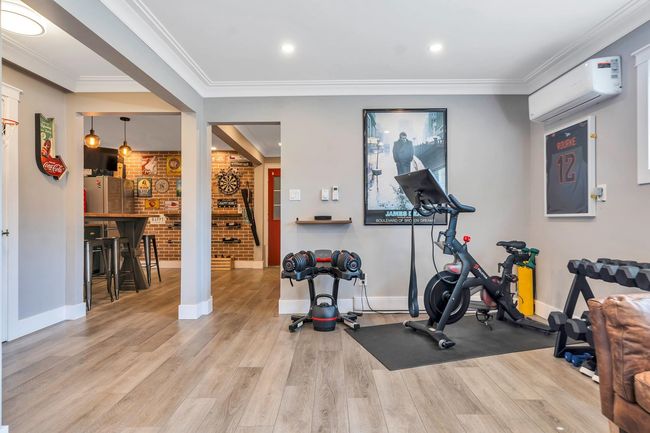 Workout room with baseboards, a wall unit AC, wood finished floors, and crown molding | Image 36