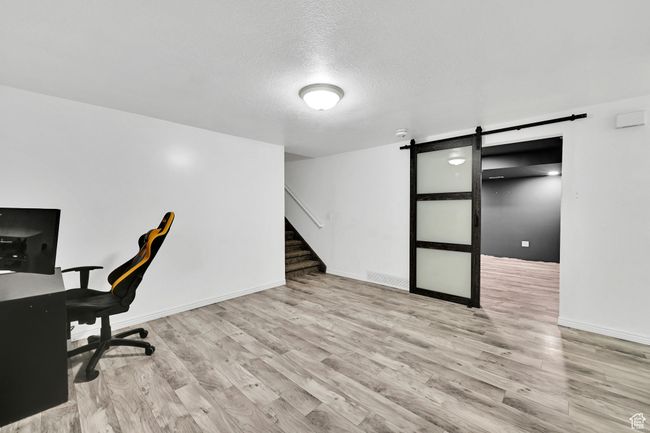 Unfurnished office with baseboards, a textured ceiling, a barn door, and wood finished floors | Image 27