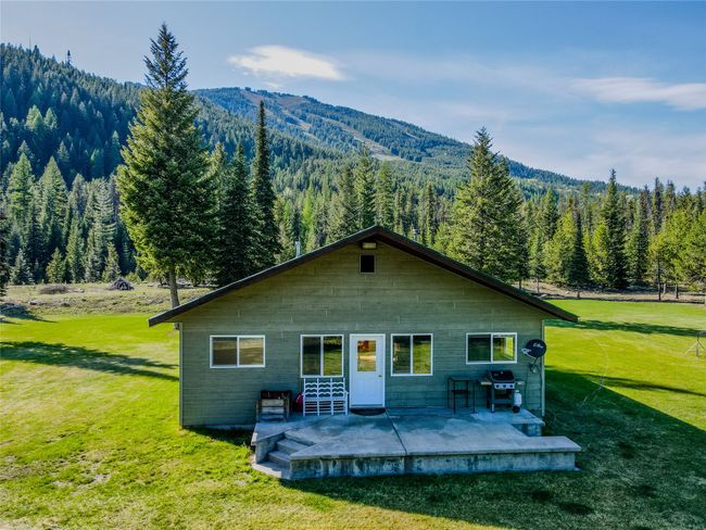 Rear view of house with a view of trees, a lawn, a mountain view, and a patio area | Image 75