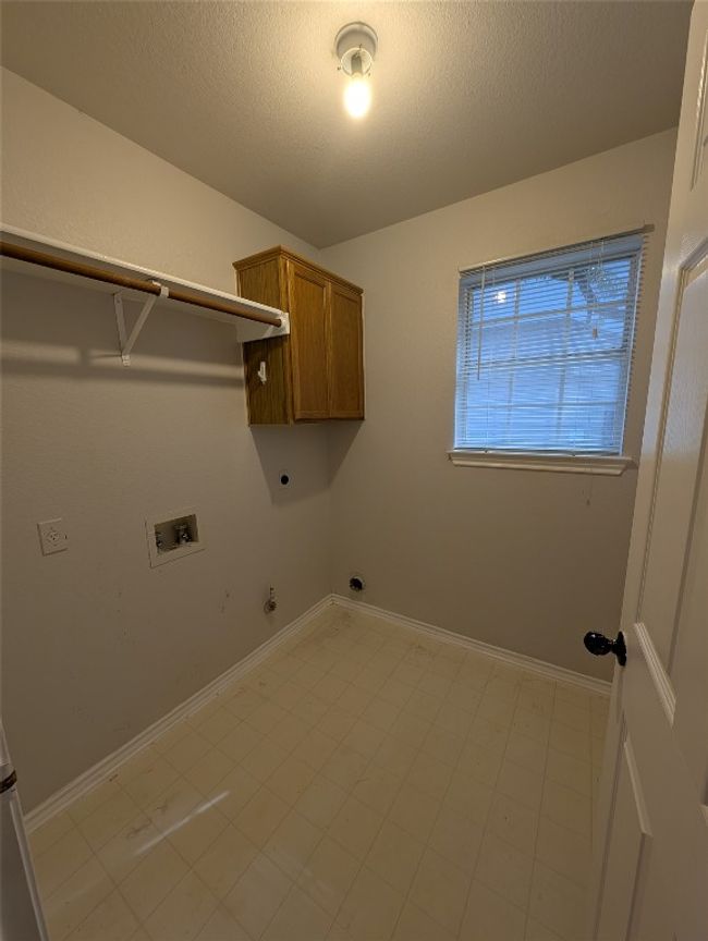Laundry room featuring gas dryer hookup, electric dryer hookup, hookup for a washing machine, cabinet space, and a textured ceiling | Image 23