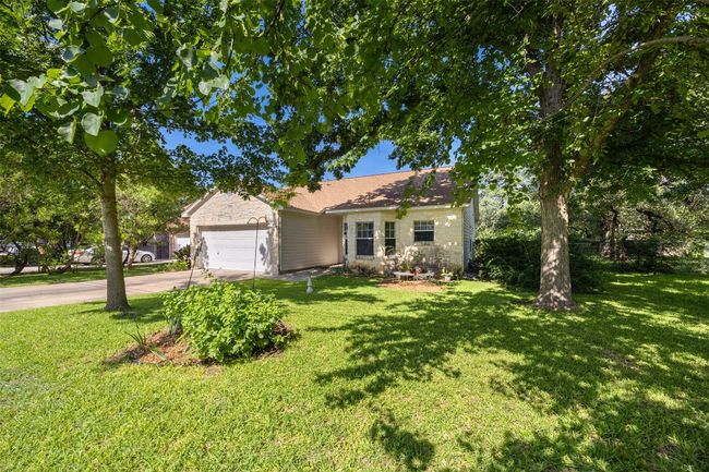 View of front of home with an attached garage, concrete driveway, a front yard, and stone siding | Image 24