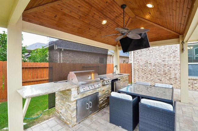 Cabana with a built-in grill, sink, granite countertops, TV and ceiling fan. | Image 44
