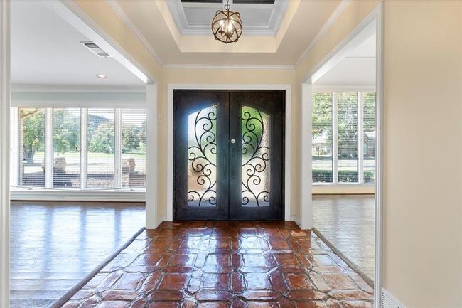 Entrance foyer with french doors, a chandelier, dark wood-type flooring, a tray ceiling, and ornamental molding | Image 33