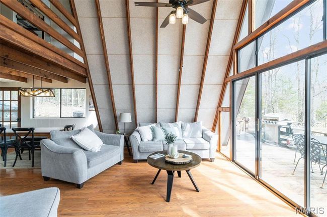 Living room with a high ceiling, light wood-type flooring, and a wealth of natural light | Image 8