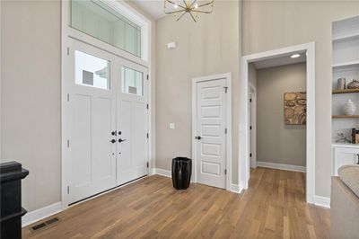 Foyer with a notable chandelier, a high ceiling, and light hardwood / wood-style floors | Image 2