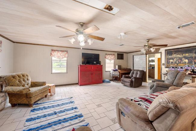 Living room with ceiling fan, visible vents, and crown molding | Image 10