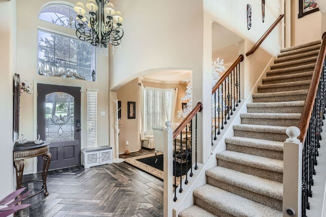 Foyer entrance featuring arched walkways, a high ceiling, a chandelier, and stairway | Image 5