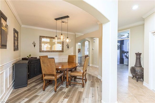 Dining room with crown molding, visible vents, arched walkways, and light wood finished floors | Image 4