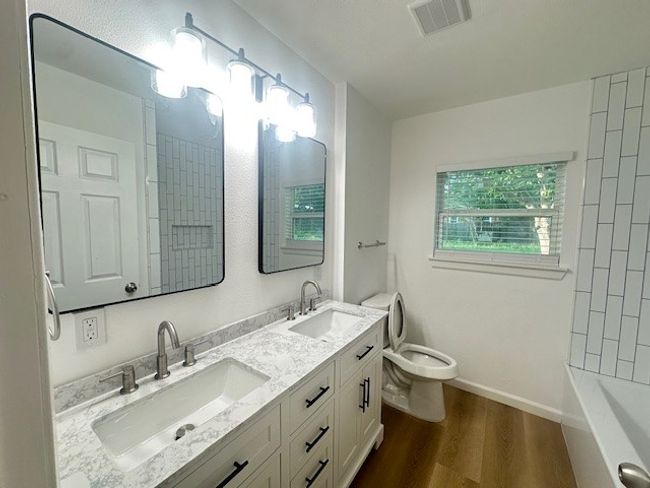 Full bath with toilet, wood finished floors, double vanity, and baseboards | Image 17