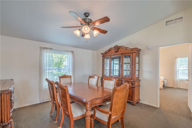 Dining space featuring carpet floors, vaulted ceiling, a ceiling fan, and baseboards | Image 11