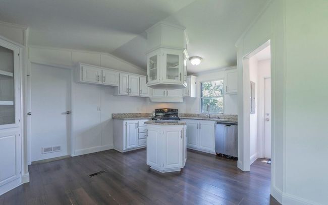 Kitchen with a center island, white cabinetry, dark wood-type flooring, dishwasher, and black range with electric cooktop | Image 7