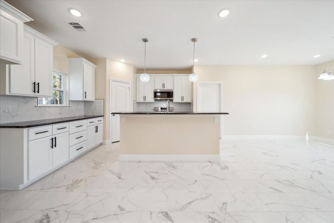 Kitchen featuring pendant lighting, a center island with sink, white cabinetry, and tasteful backsplash | Image 8