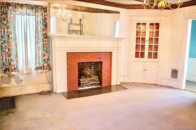 Unfurnished living room with a chandelier, a fireplace, and carpet flooring | Image 11