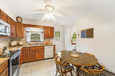 Kitchen with decorative backsplash, stainless steel appliances, sink, light tile patterned floors, and ceiling fan. | Image 3