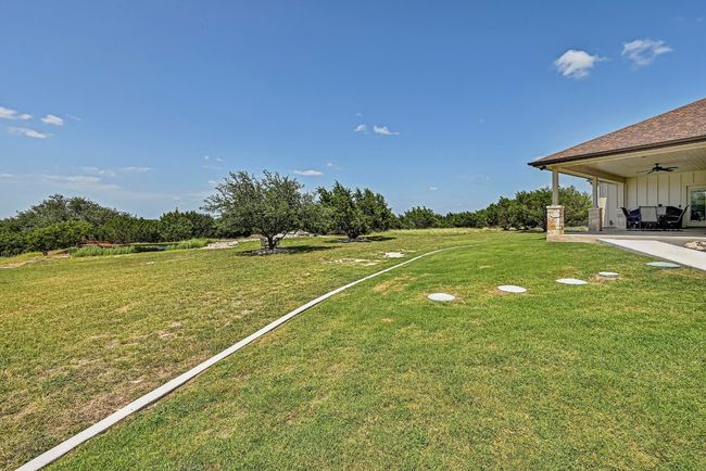 View of green lawn featuring a ceiling fan and a patio | Image 33