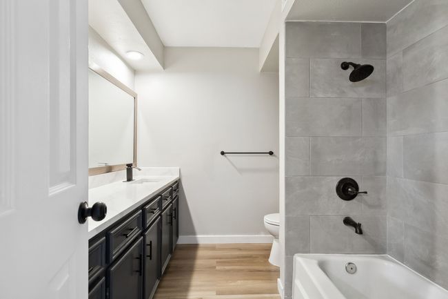 Bathroom with wood finished floors, toilet, shower / bathtub combination, vanity, and baseboards | Image 29