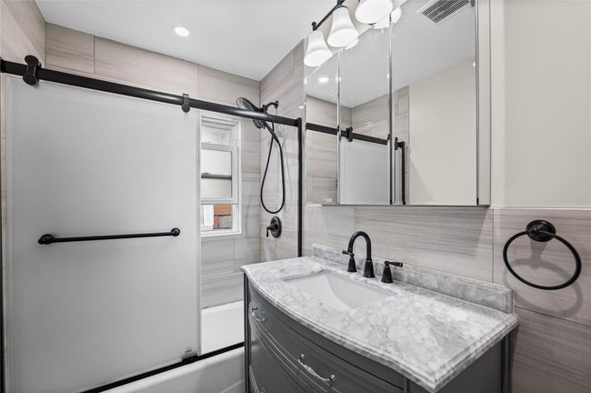 Full bath with tile walls, enclosed tub / shower combo, vanity, and recessed lighting | Image 24