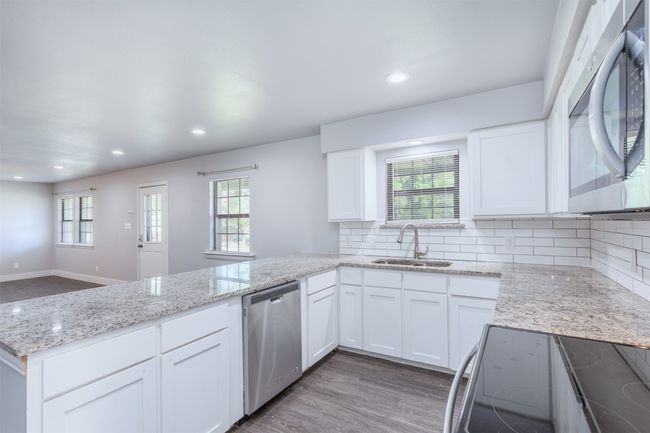 Kitchen with a peninsula, white cabinets, stainless steel appliances, and a sink | Image 11