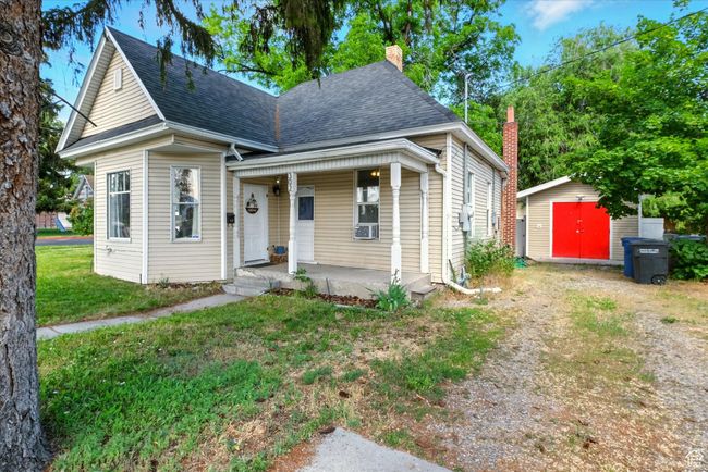 Shotgun-style home with a porch, a storage shed, a chimney, roof with shingles, and a front yard | Image 22