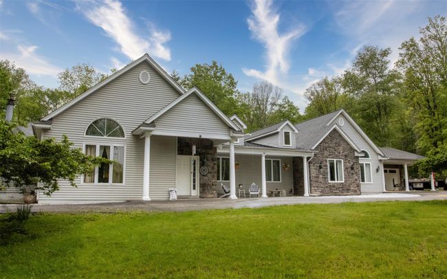View of front of home with stone siding, a front lawn, and a porch | Image 5