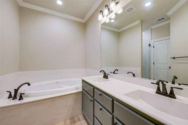 Full bath with a garden tub, crown molding, wood finished floors, recessed lighting, and double vanity | Image 11