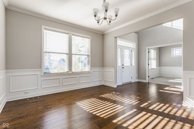 unfurnished room featuring hardwood / wood-style floors, a wainscoted wall, an inviting chandelier, visible vents, and a decorative wall | Image 6