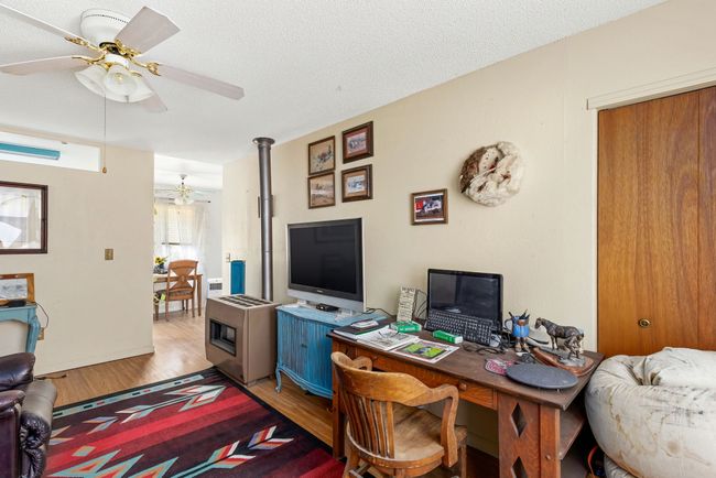 Home office with light wood finished floors, a textured ceiling, baseboards, and a ceiling fan | Image 66