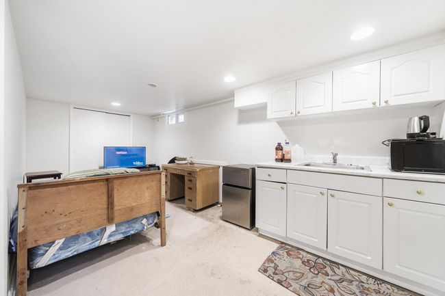 Kitchen featuring white cabinets, recessed lighting, unfinished concrete flooring, a sink, and freestanding refrigerator | Image 25