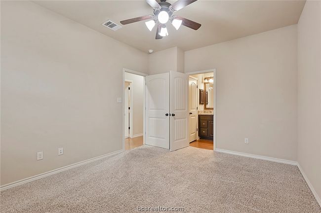 Unfurnished bedroom with light colored carpet, baseboards, ensuite bathroom, and visible vents | Image 7