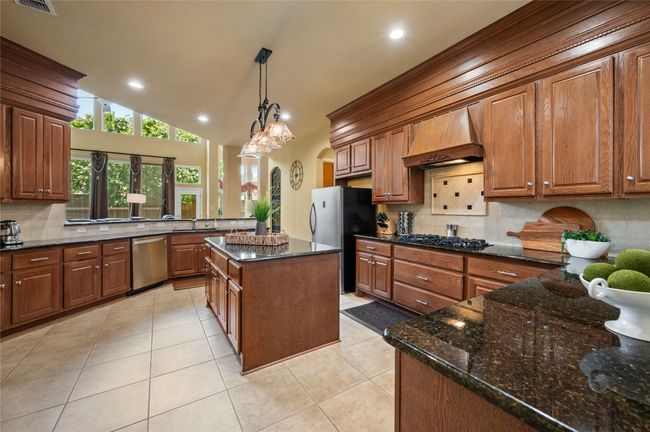 Kitchen featuring stainless steel appliances, tasteful backsplash, light tile patterned flooring, recessed lighting, and brown cabinets | Image 18