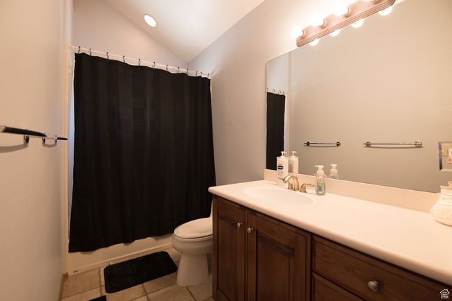 Full bathroom featuring lofted ceiling, tile patterned floors, toilet, vanity, and shower / tub combo | Image 78