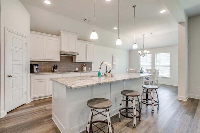 Kitchen featuring a sink, white cabinetry, light wood-style flooring, backsplash, and lofted ceiling | Image 11