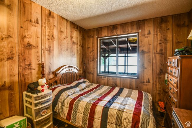 Bedroom featuring wooden walls and a textured ceiling | Image 38