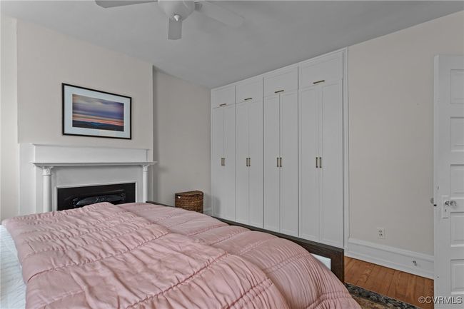 Bedroom with baseboards, a ceiling fan, wood finished floors, a closet, and a fireplace | Image 20