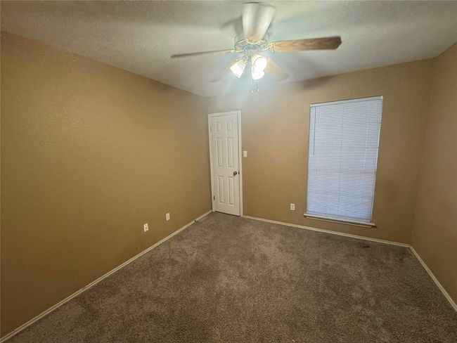 Carpeted empty room featuring a ceiling fan and a textured ceiling | Image 13