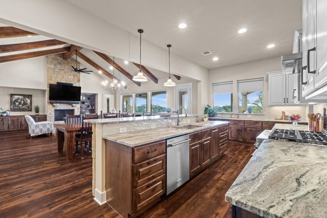 Kitchen with dishwasher, a stone fireplace, a sink, open floor plan, and white cabinetry | Image 14