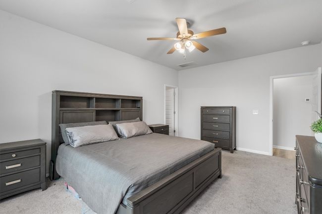 Bedroom featuring light colored carpet, a ceiling fan, and baseboards | Image 14